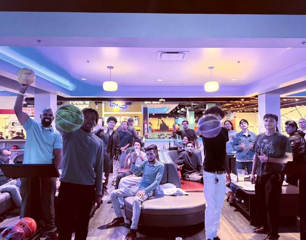 A large group of diverse young male and female professionals in business attire posing together in a luxury lounge for a success photo.